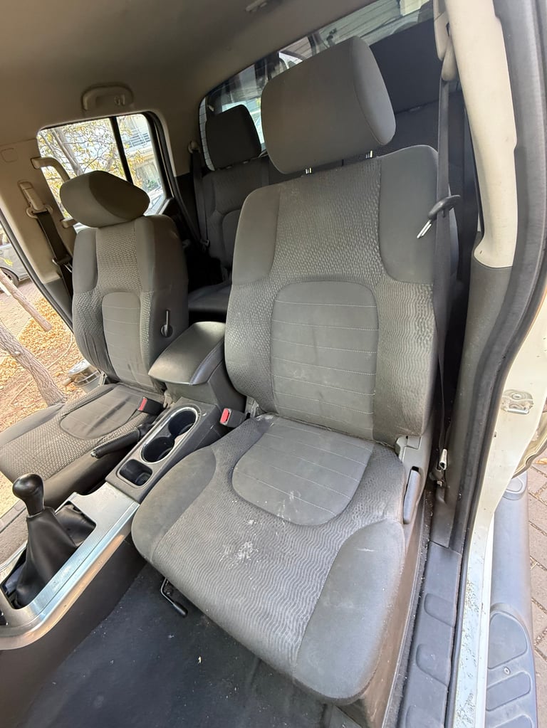 Interior view of a vehicle showing gray fabric car seats with door open, viewed from the side