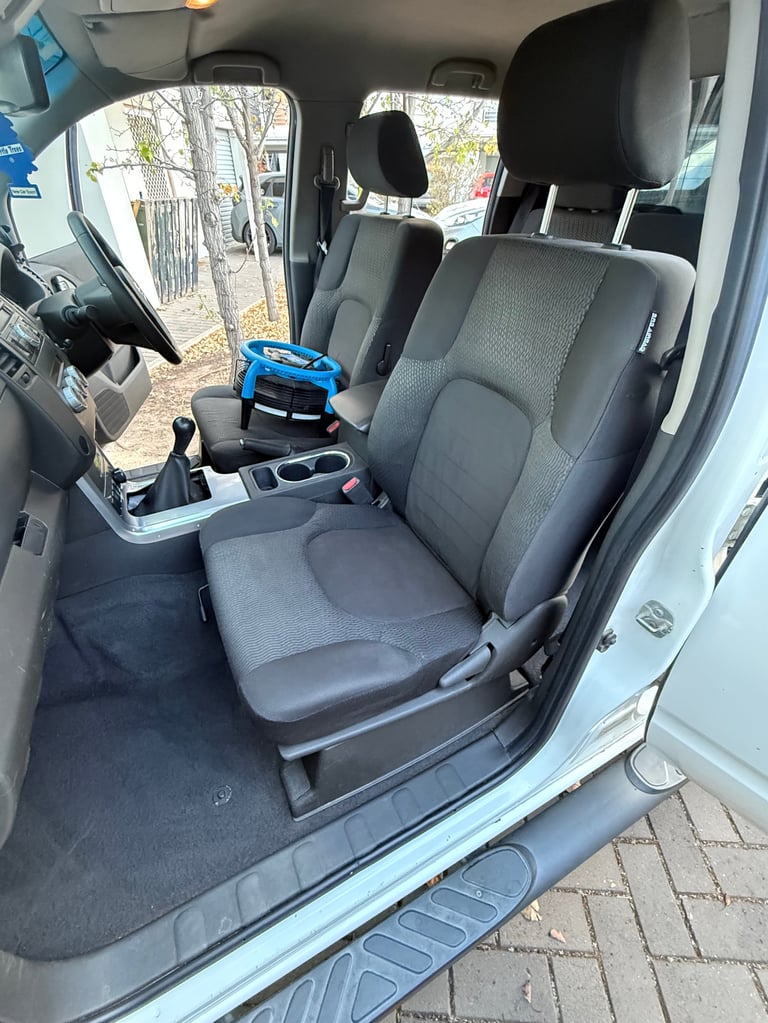 Interior view of vehicle showing gray and black upholstered front seats, steering wheel, and console with a blue handbag visible on the center seat