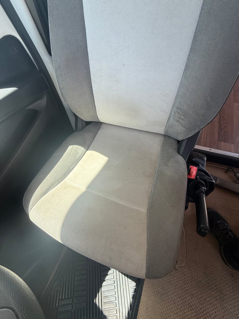 Car seat with gray and white fabric upholstery, viewed from above inside a vehicle